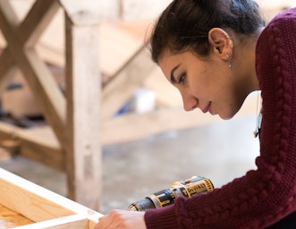 Woman drills a frame on our Tiny house course