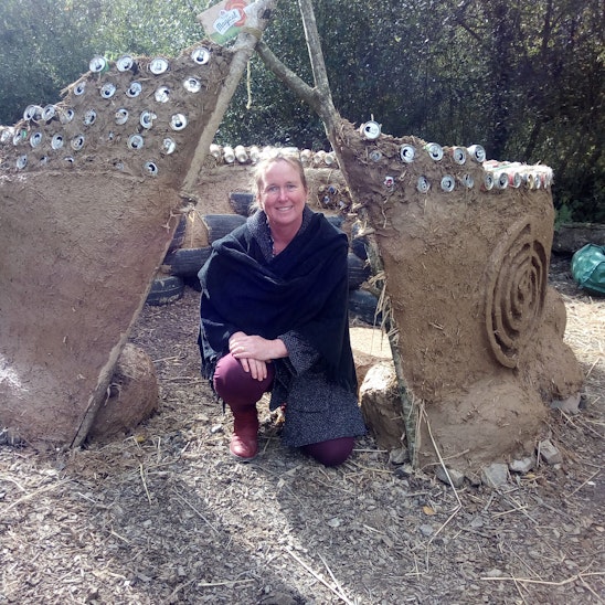 Lizzie Wynn with a partially built cob and ecobricks building