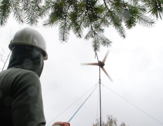 Man looks up at a small wind turbine
