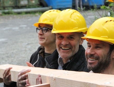 Close up o f people carrying a timber frame