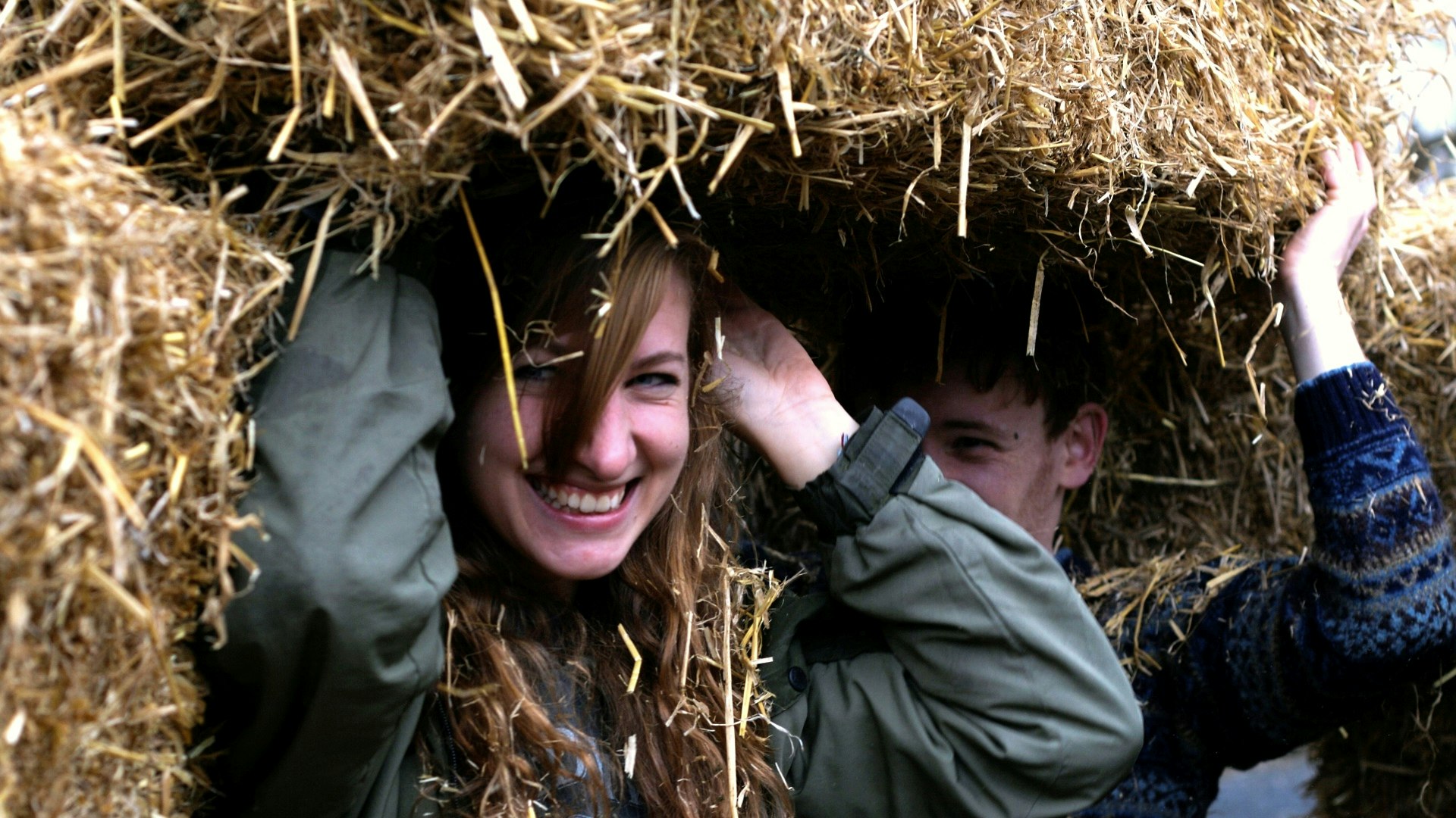 Women holding up a straw bale