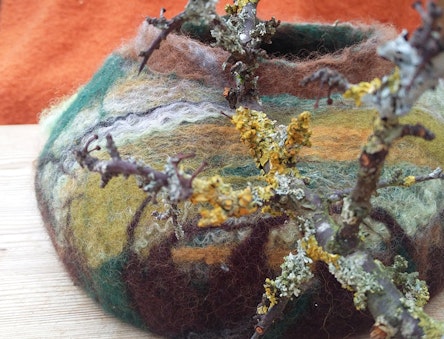 felt bowl and branches of wood with lichen on