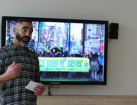 Man in front of a screen with a protest image on it