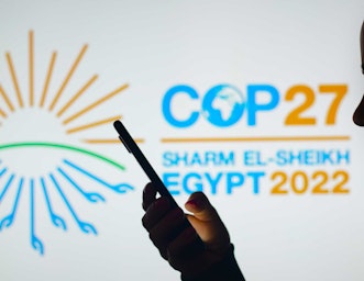 COP27 Logo with silhouette of someone holding their phone in front. (Credit rafapress / Shutterstock)