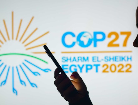 COP27 Logo with silhouette of someone holding their phone in front. (Credit rafapress / Shutterstock)