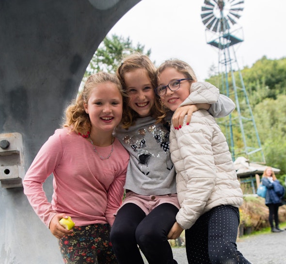 Children hugging looking through a wind turbine hub