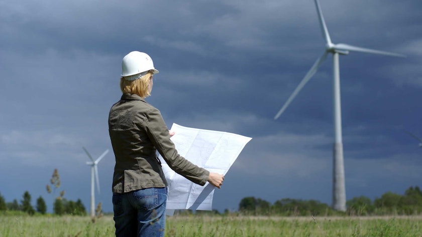 Women looking at a plan in front of some wind turbines
